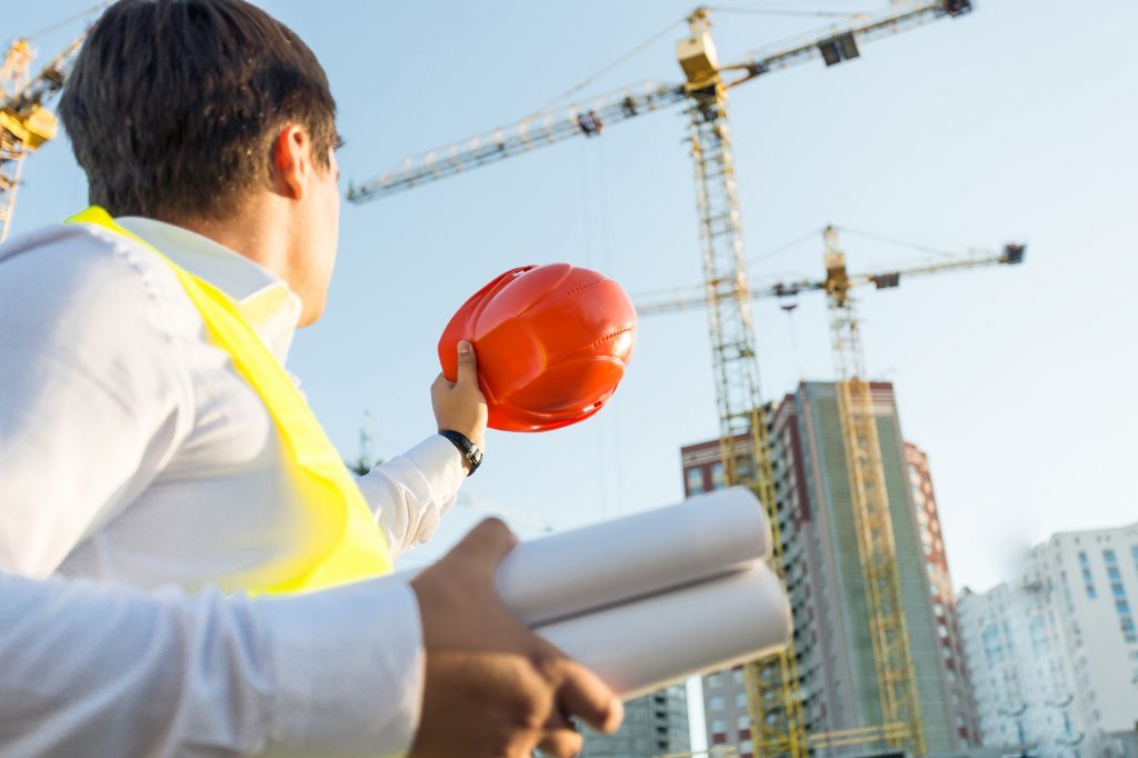 Closeup of engineer posing on building site with orange hardhat